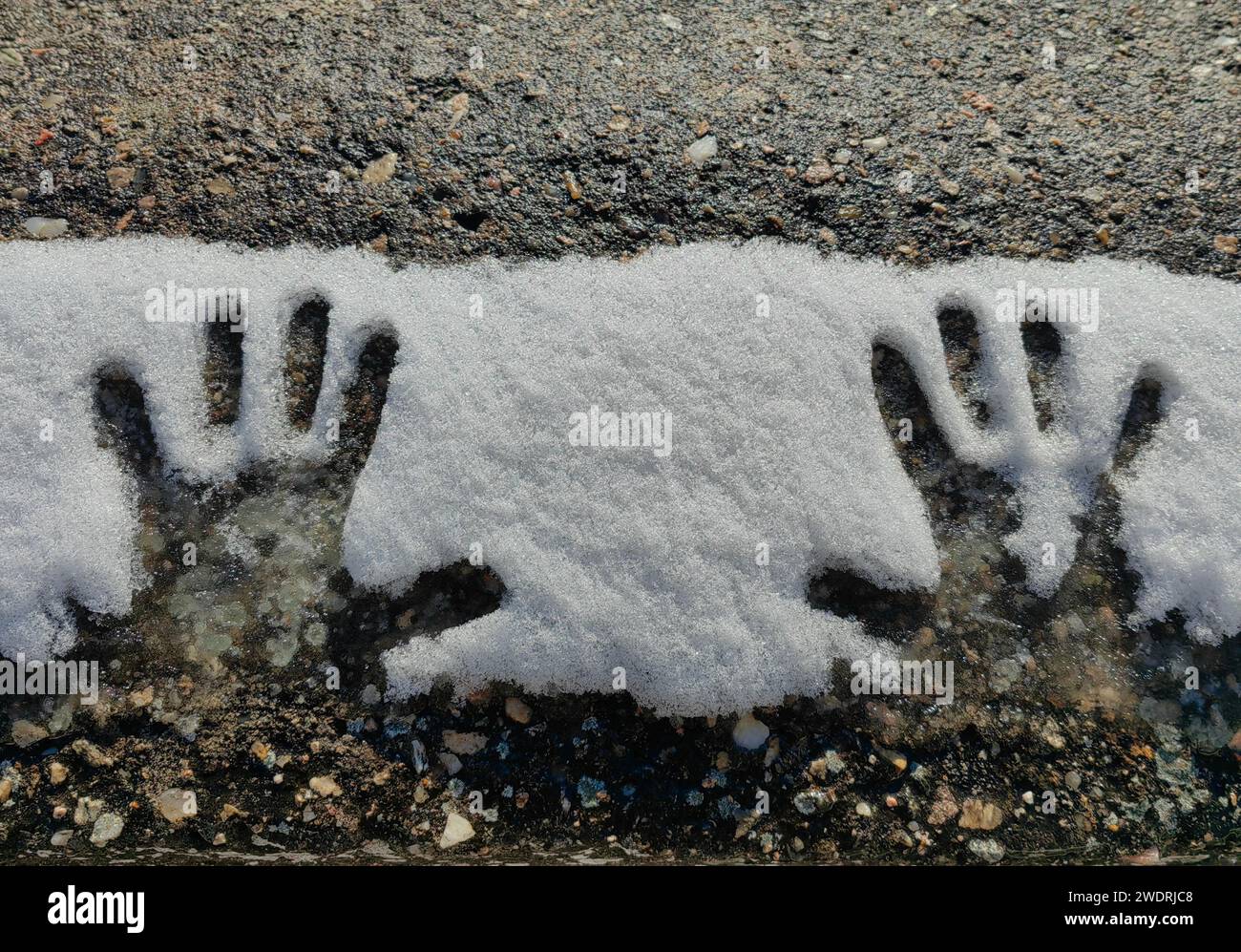 Le mani del bambino, nella neve. Spazio nero. Pavimento in calcestruzzo, monocromatico. Foto Stock