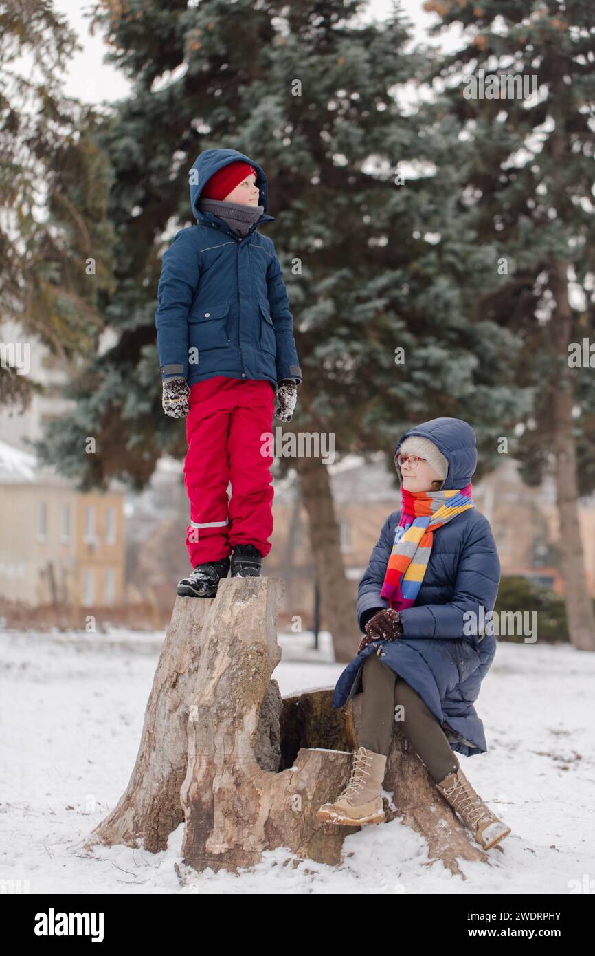 I bambini si riposano su un ceppo nel parco Foto Stock