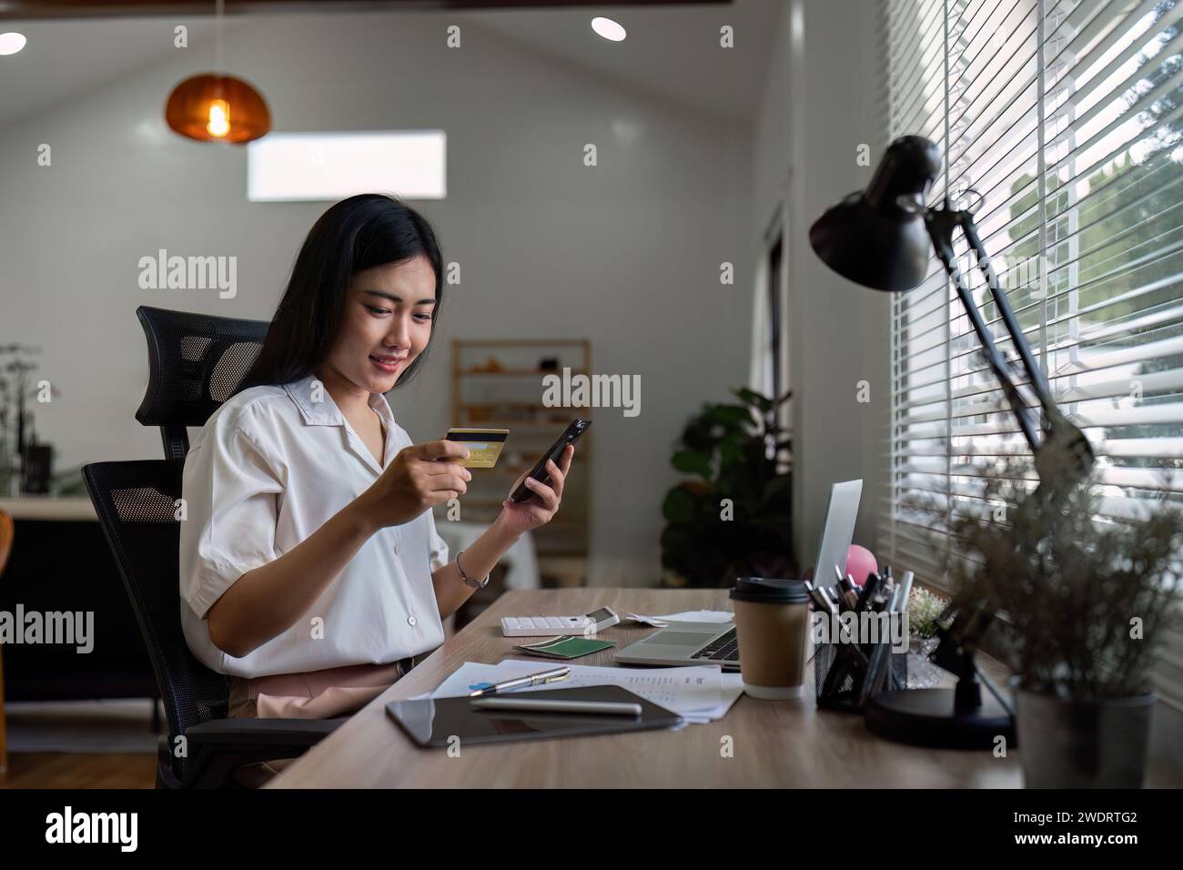 donna che utilizza il telefono cellulare per effettuare pagamenti online in modo facile e sicuro nel sistema bancario elettronico. La giovane cliente spende soldi dalla carta di credito Foto Stock