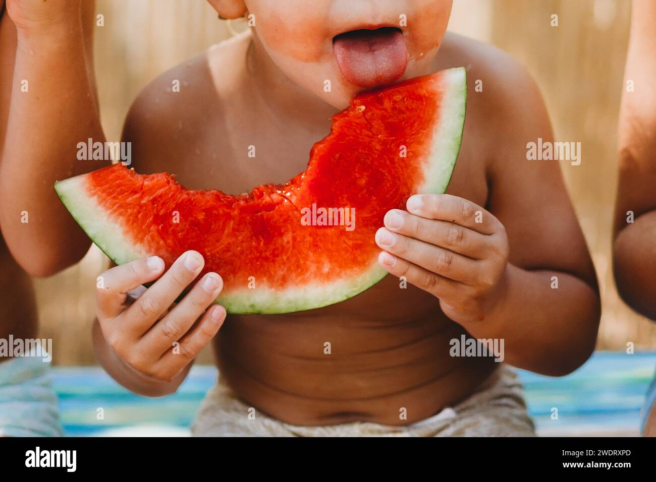 Bambino piccolo leccare fetta di anguria nella calda giornata estiva in Spagna Foto Stock