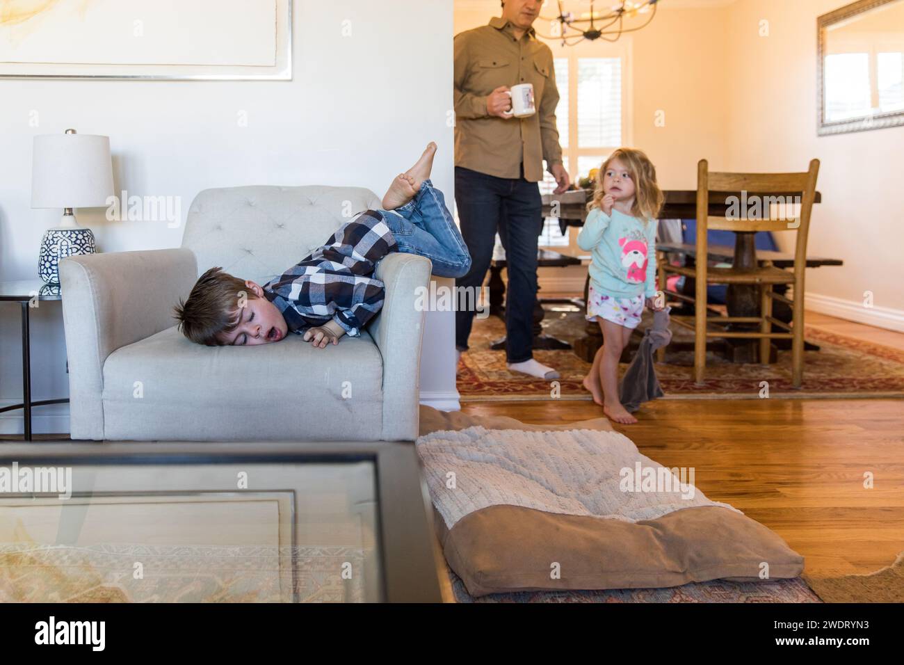 Giovane ragazzo che salta sulla sedia mentre la sorella guarda il pigiama Foto Stock