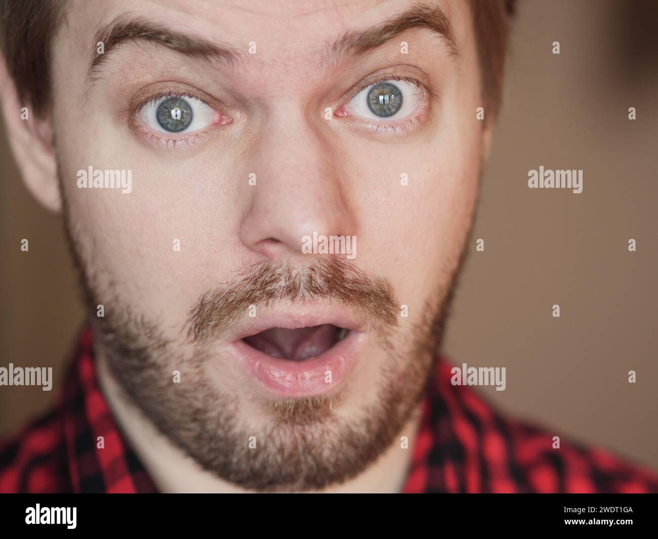 Un uomo con una faccia sorpresa. Ritratto su sfondo beige. Foto Stock