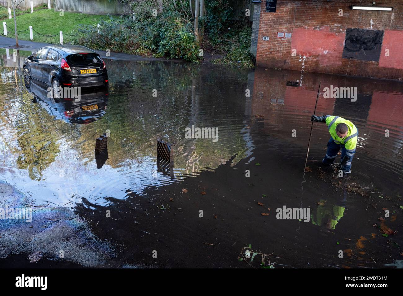 Un operaio sorveglia il drenaggio di una strada allagata e un'auto rimane abbandonata sotto il ponte ferroviario sull'East Dulwich Grove nel Dulwich Village, dopo una perdita d'acqua in un vicino incrocio stradale, il 22 gennaio 2024, a Londra, in Inghilterra. Foto Stock
