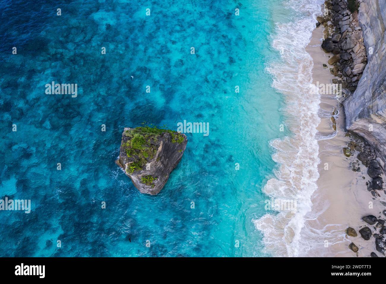 Vista aerea della spiaggia di sabbia bianca di Suwehan con acqua di mare turchese e la grande roccia (pila di mare) nel mare vista da un drone, Nusa Penida Foto Stock