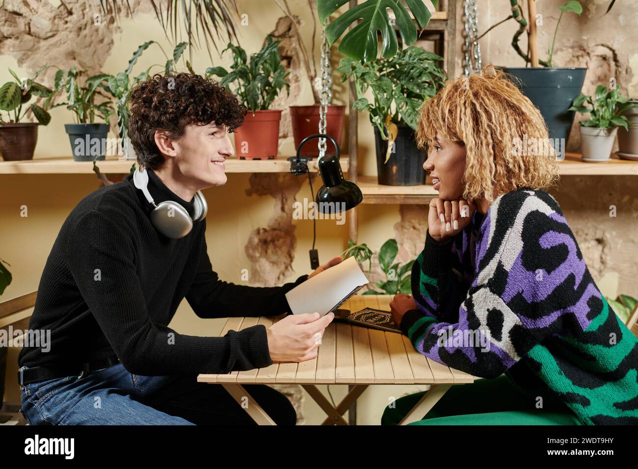 vista laterale di diverse coppie romantiche che si guardano l'un l'altro sul menu durante la data in un caffè vegan Foto Stock