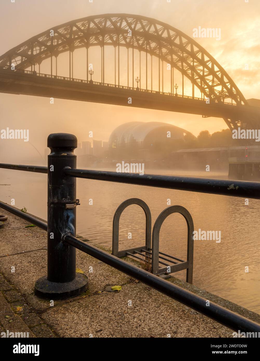 Tyne Bridge e Quayside su un moring dorato e nebbioso in autunno.incorniciato da ringhiere. Formato verticale Foto Stock