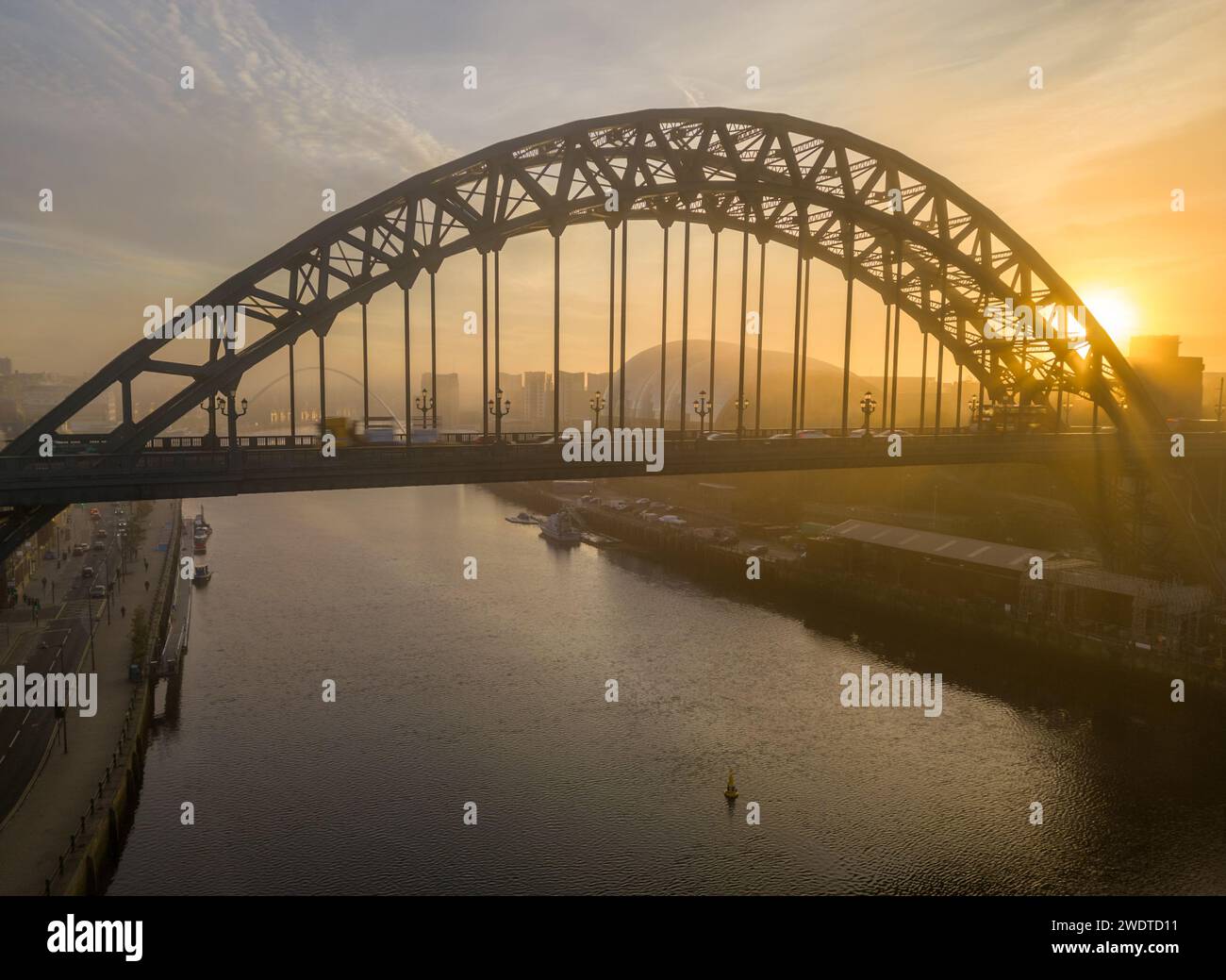 Colpo di drone di sole nebbioso che sorge dietro il ponte tyne e il centro salvia a Newcastle Foto Stock