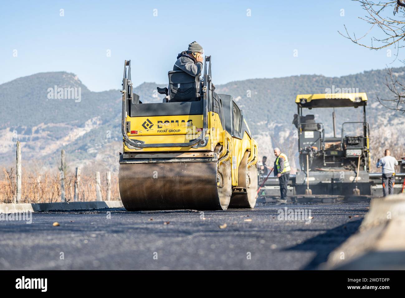 Materiale fotografico di magazzino per cantieri stradali, posa di una nuova superficie di asfalto, macchine per impieghi gravosi, lavoratori edili, lavori di pavimentazione Foto Stock