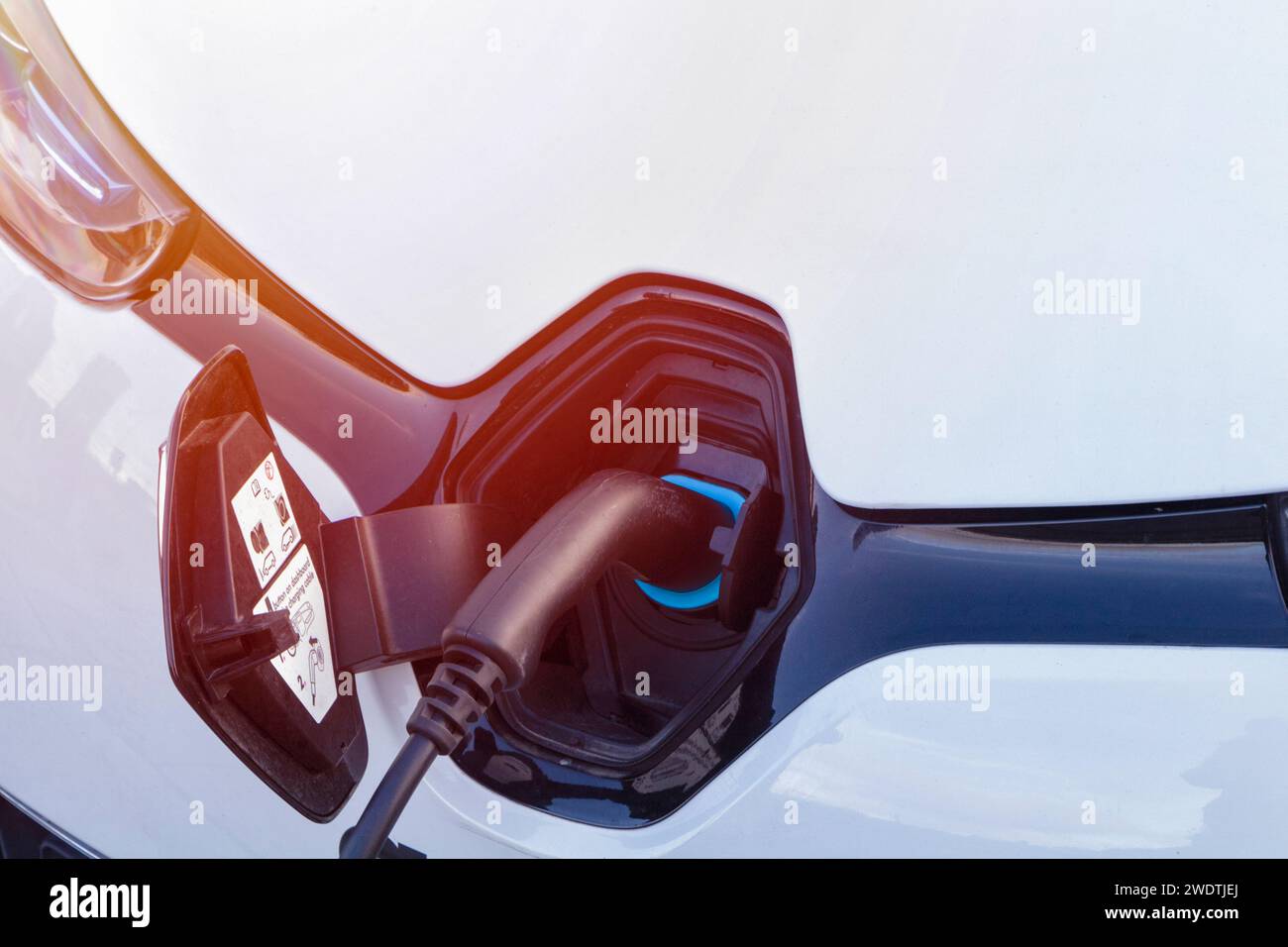 Auto elettrica alla stazione di ricarica con il cavo di alimentazione collegato. Uso di tipi di energia alternativi. Processo di carica. Foto Stock