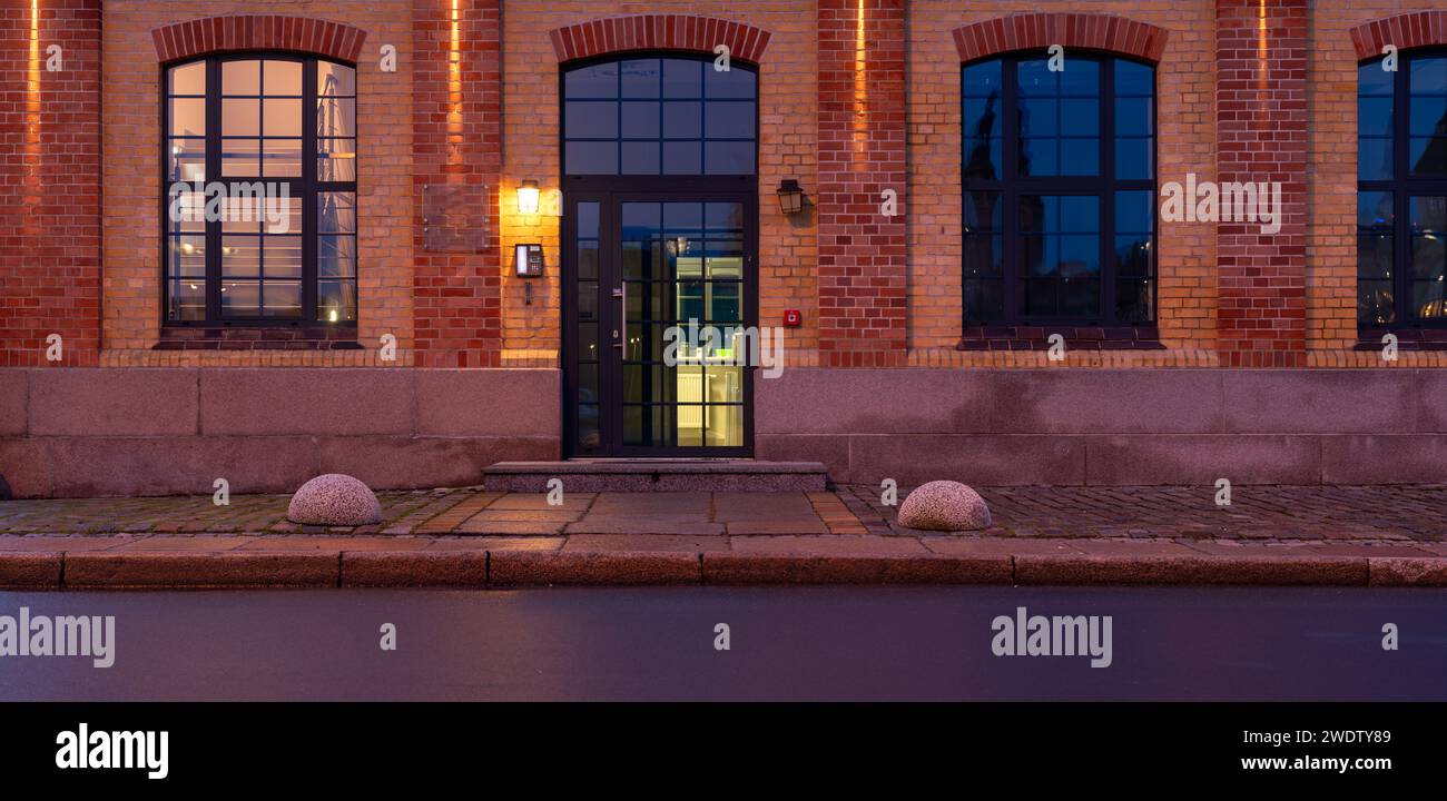 La facciata dell'edificio storico insieme alla pavimentazione in granito illuminata dalla luce dei lampioni Foto Stock