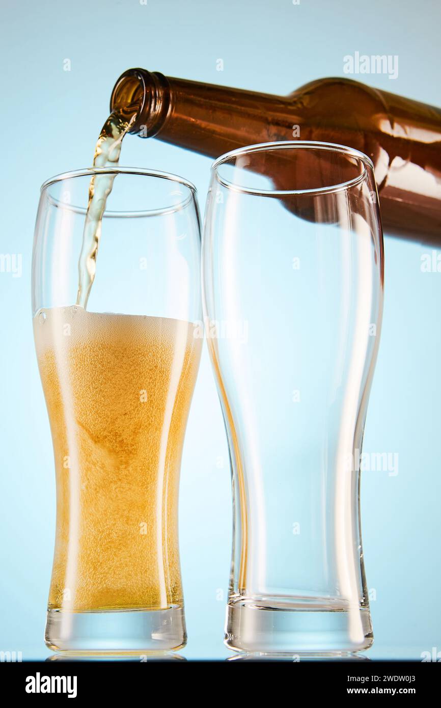 La birra viene versata dal mockup di una bottiglia color ambra ai bicchieri. Foto Stock