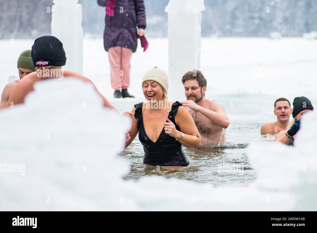 Gruppo di persone ghiacciate che nuotano insieme nell'acqua fredda gelida di un lago ghiacciato. Metodo Wim Hof, terapia fredda, tecniche respiratorie, yoga Foto Stock