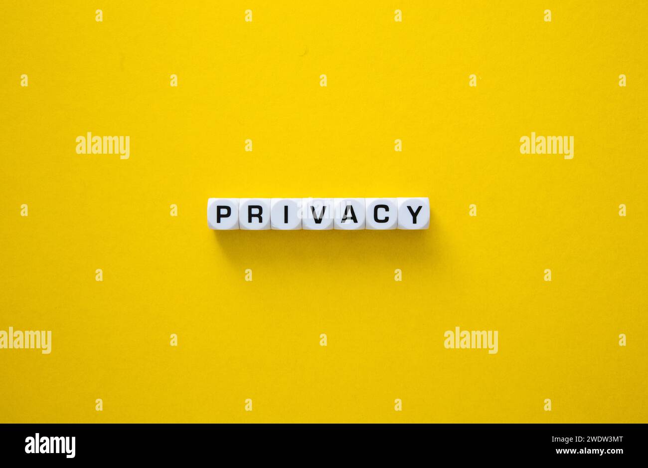 Parola privacy rappresentata con cubi di lettere, simbolizzanti la sicurezza dei dati e le informazioni personali su una superficie gialla Foto Stock
