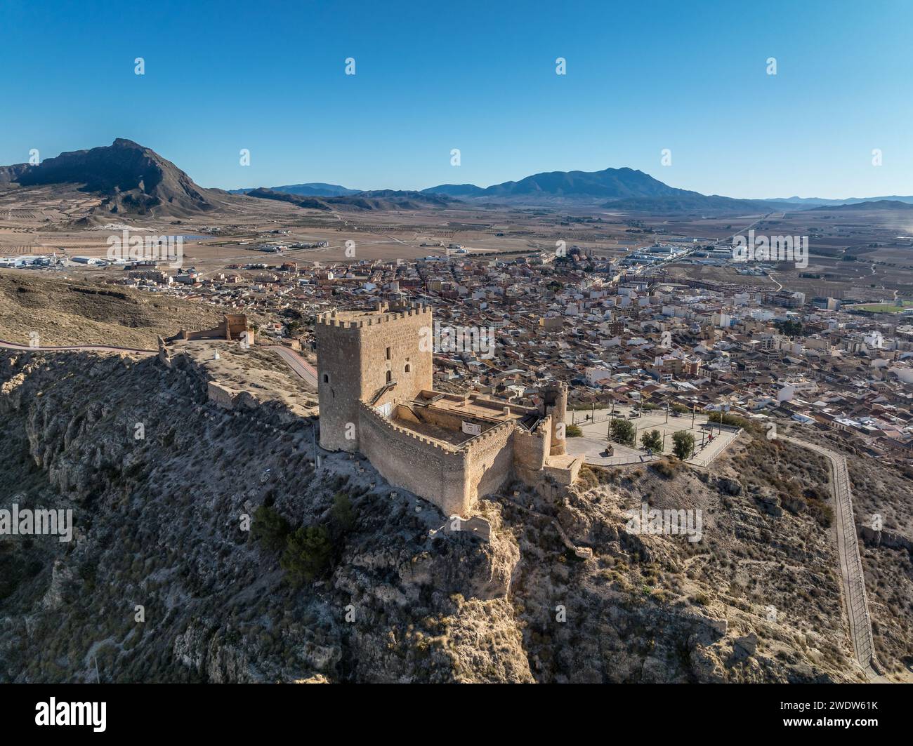 Vista aerea del castello medievale di Jumilla a Murcia in Spagna, su una collina, imponente struttura di forma irregolare a quattro piani, merlature merlate nuvolose Foto Stock