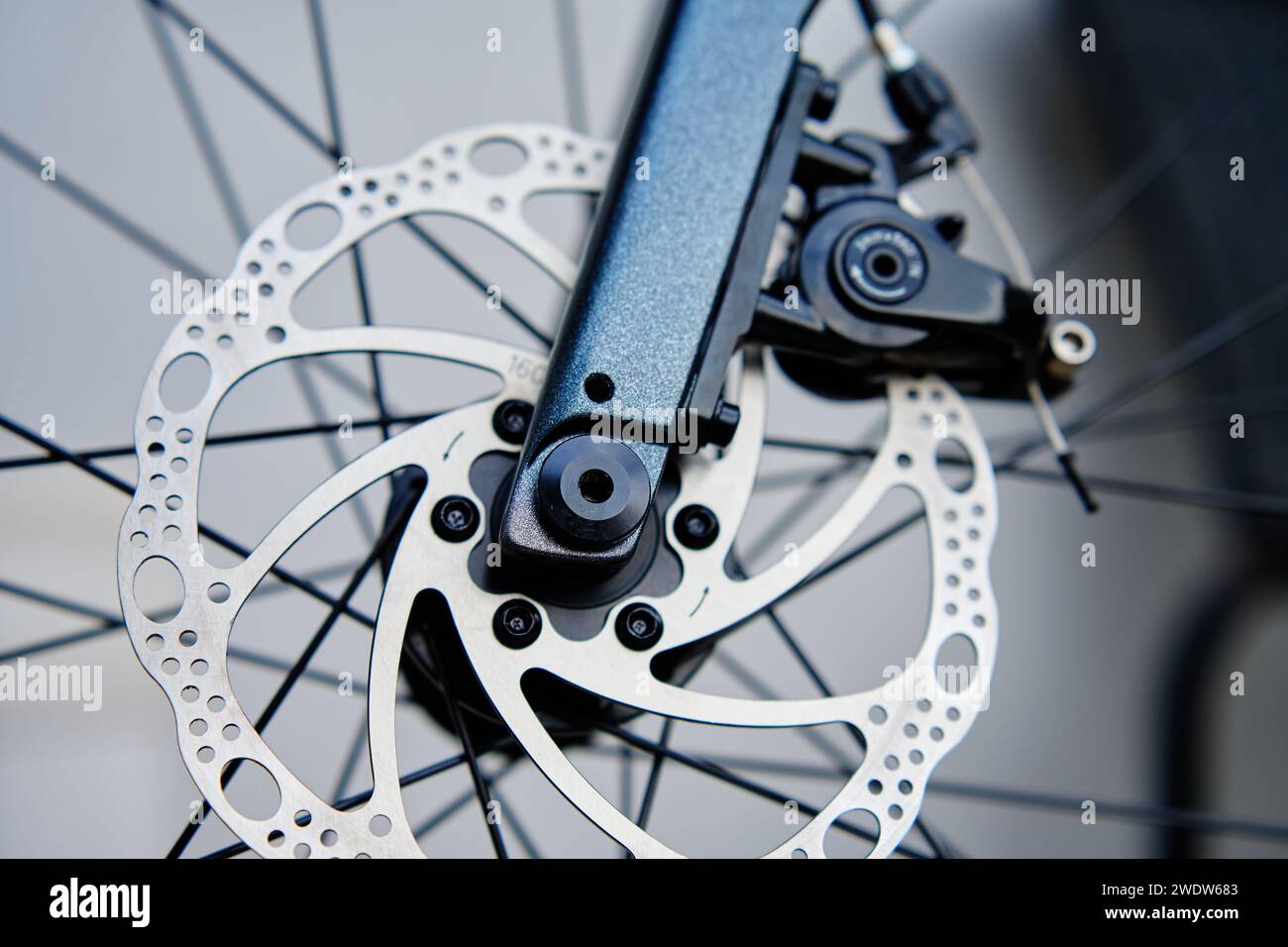 Parte dell'impianto frenante della bicicletta. Disco freno e pastiglie dei freni in metallo grigio sulla bici da strada, primo piano. Foto Stock