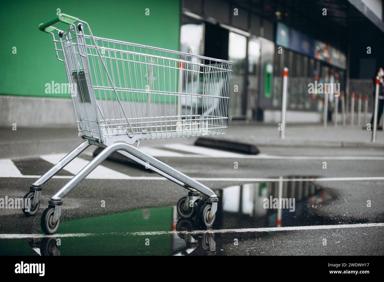 un cestino del supermercato è sull'asvalt e una pozza d'acqua, una sedia a rotelle. Foto di alta qualità Foto Stock