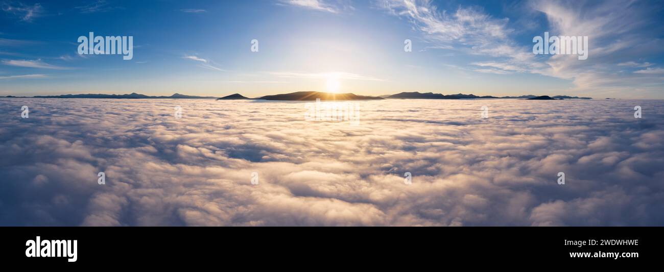 Paesaggio sopra le nuvole con cime montuose all'alba. Spettacolare paesaggio nuvoloso dalla vista aerea. Foto Stock