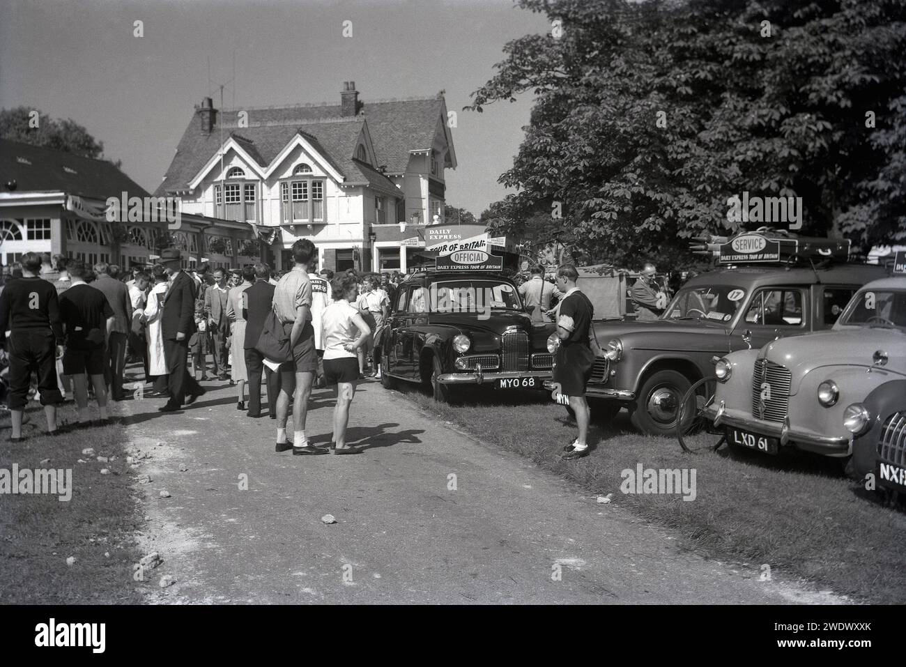 1952, storia, gente che si riunisce all'inizio di una tappa della corsa ciclistica dilettante Daily Express Tour of Britain, Inghilterra, Regno Unito. Nella foto sono illustrate le vetture ufficiali e un veicolo di servizio, con i bagagli sul portapacchi. Foto Stock
