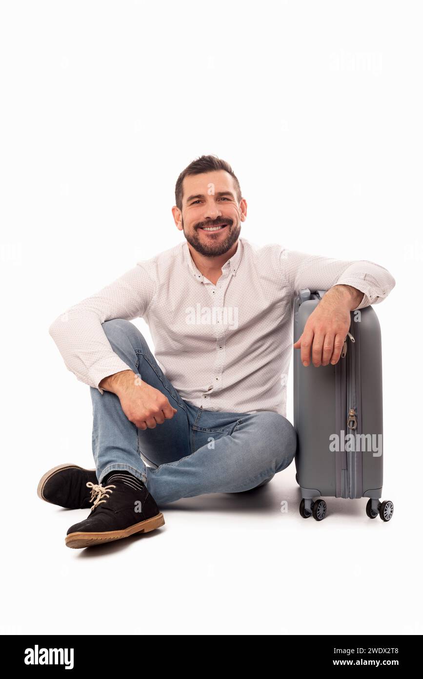 Uomo barbuto seduto con la sua valigia da viaggio. Felicità di viaggiare. Sicurezza in viaggio. Bagaglio a mano. Misurazioni consentite dalle compagnie aeree nel bagaglio Foto Stock