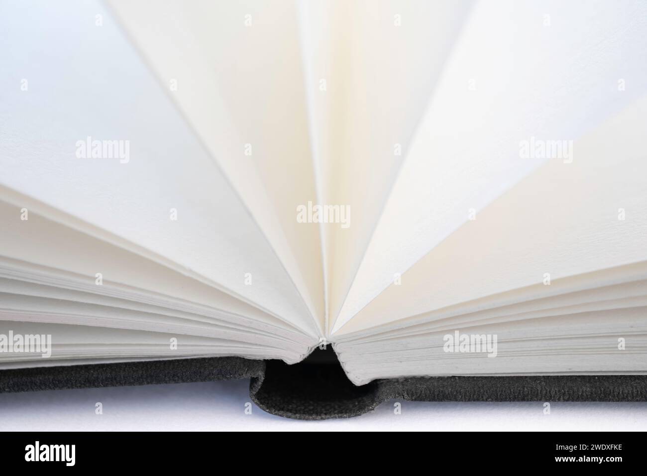 Libro aperto con pagine aperte bianche e una copertina in lino nero, isolata su sfondo bianco Foto Stock