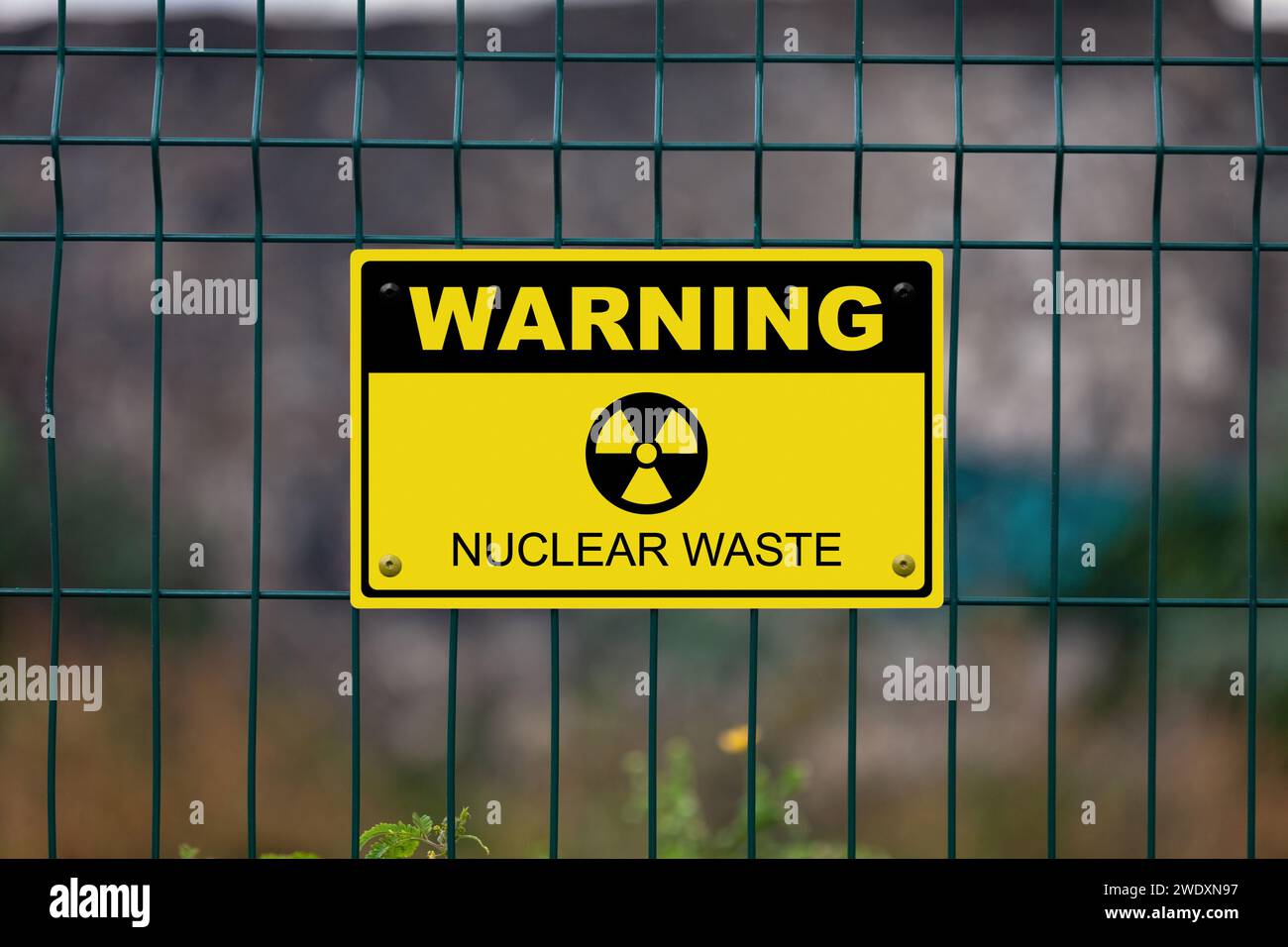 Cartello di avvertimento nero e giallo su una recinzione con un simbolo nucleare e il messaggio in "quarantena - scorie nucleari”. Foto Stock