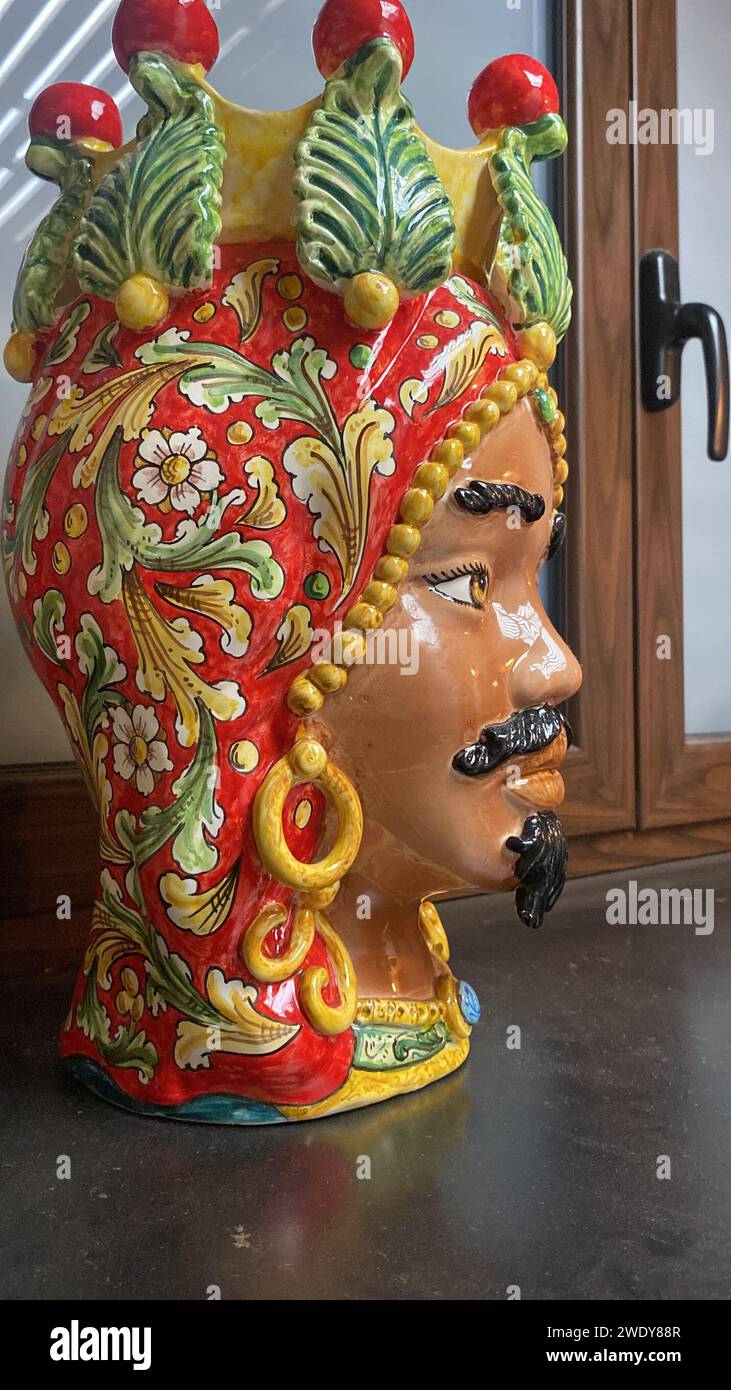 Realizzata a mano in rosso vivace, la scultura della testa dei Mori siciliani è un simbolo audace di storia e cultura, meticolosamente modellata con dettagli intricati. Foto Stock