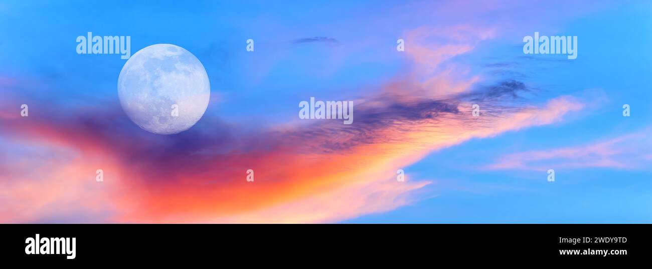 Una Luna piena sta risplendente in Un colorato Sunset Blue Daytime Sky Foto Stock