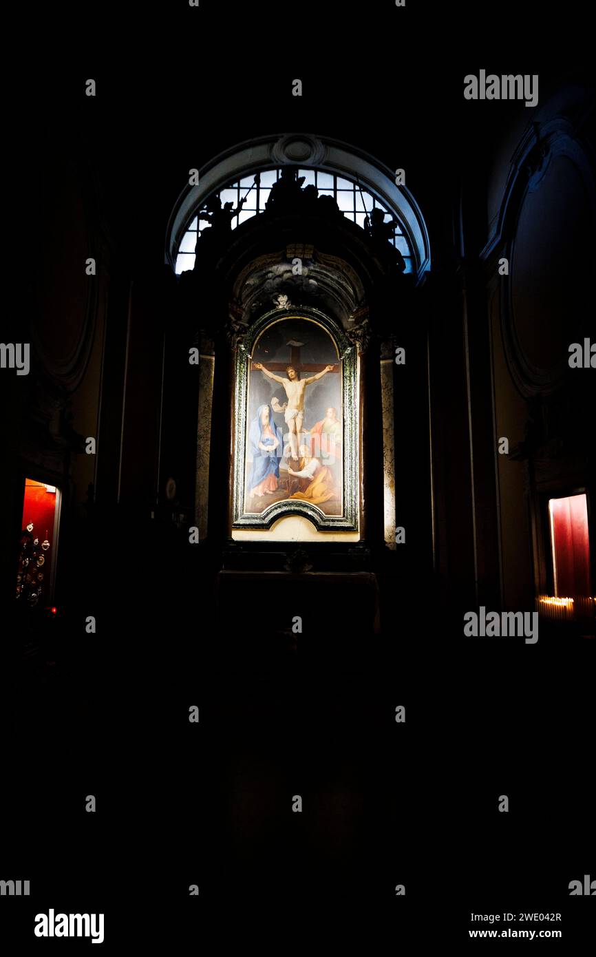 Suggestivo dipinto d'altare illuminato da candele votive a Santa Maria delle Fornaci, Roma. Foto Stock