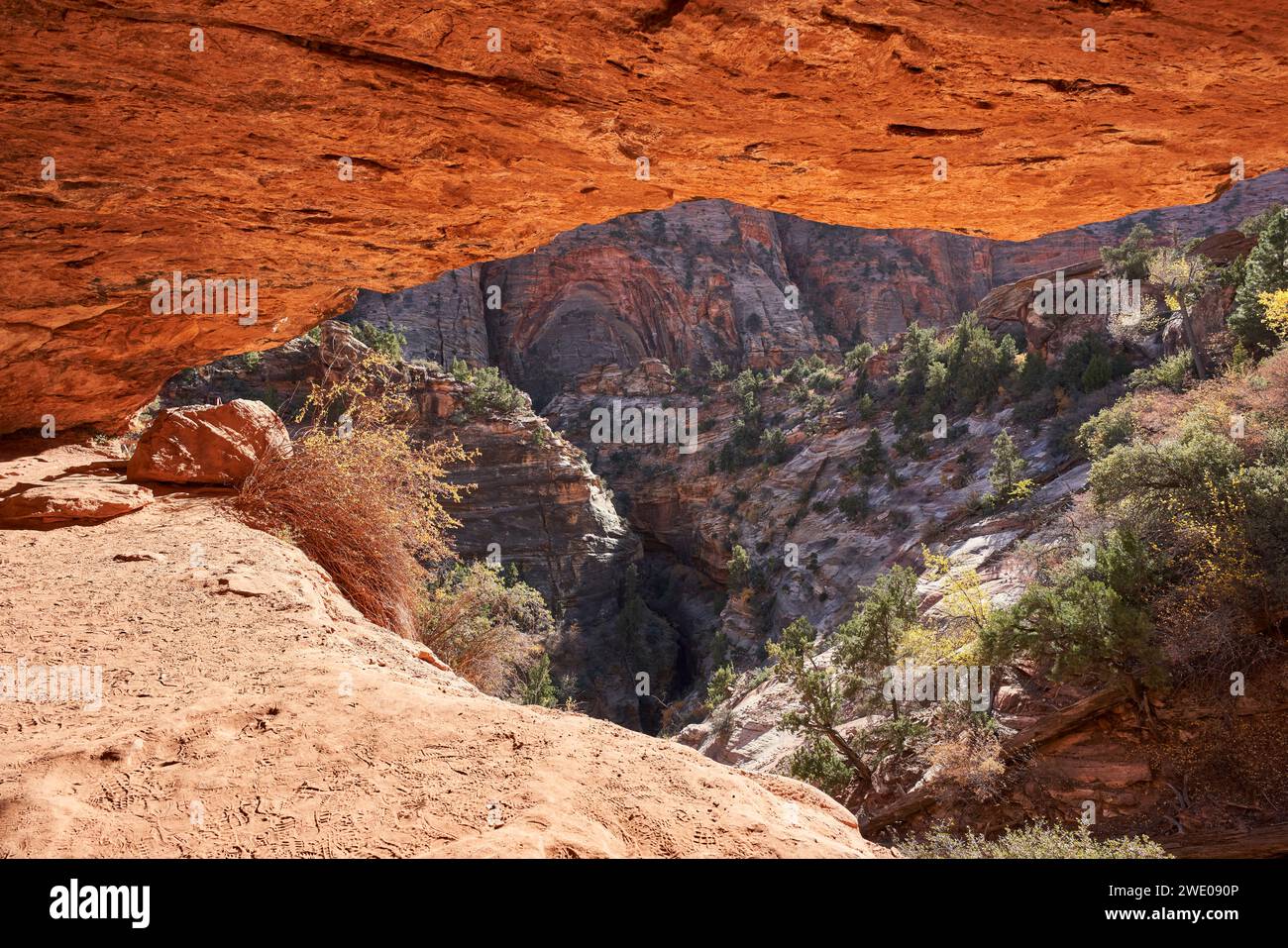 Uno strapiombo di roccia forma una grotta che si affaccia su un ripido ripido rientro nella valle sottostante. Foto Stock