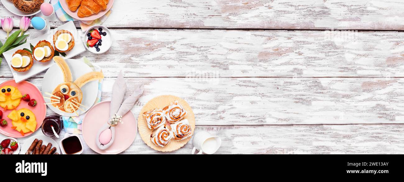 Colazione di Pasqua o brunch all'angolo. Vista dall'alto su uno sfondo di legno bianco. Pancake, nidi d'uovo, frutta di pulci e cibo primaverile assortito Foto Stock