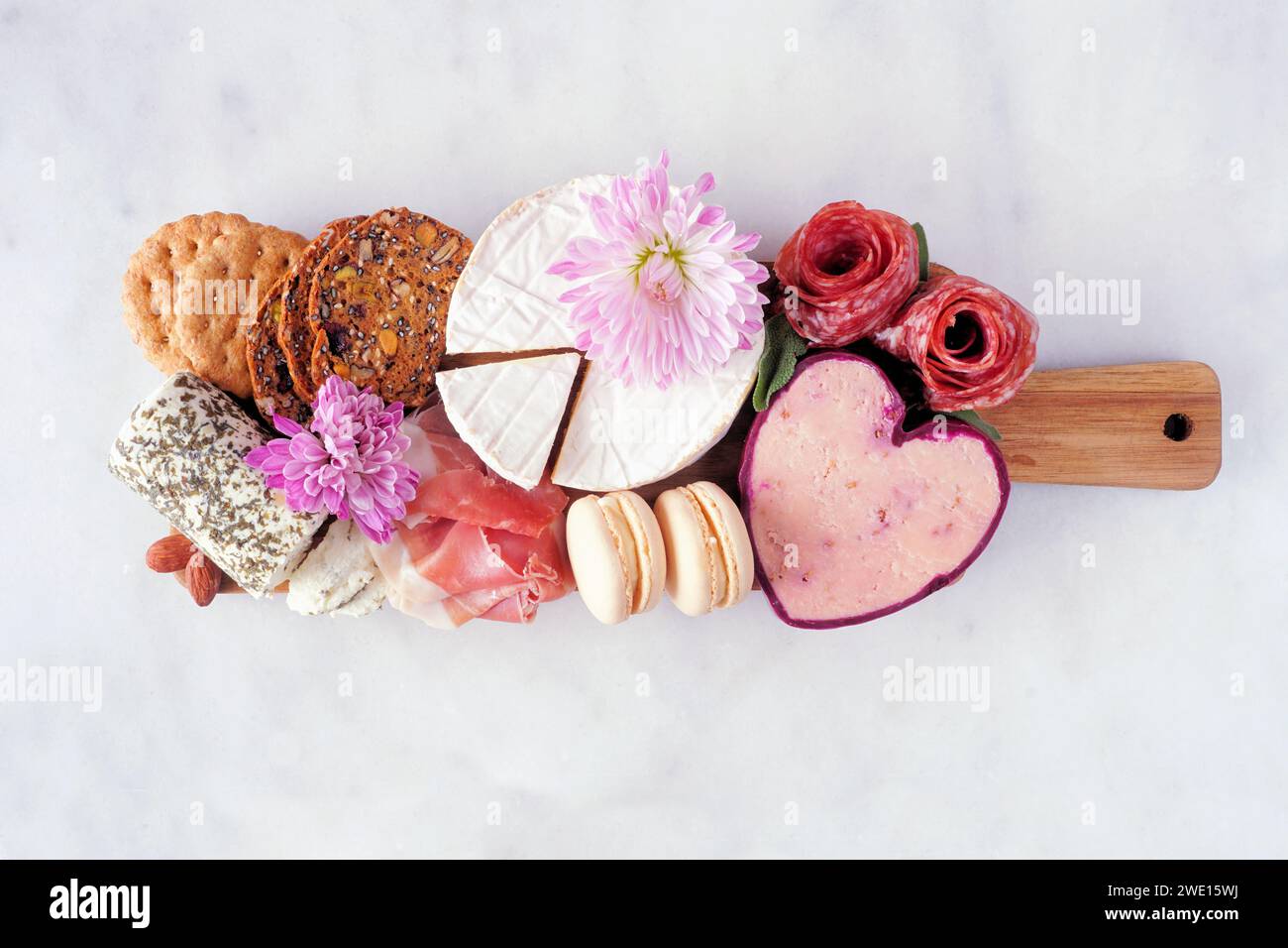 Tagliere a tema Festa della mamma su sfondo di marmo bianco. Varietà di formaggi, carne, frutta e antipasti dolci. Vista dall'alto. Foto Stock