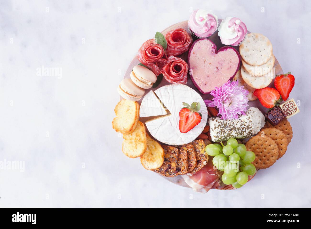 Tagliere a tema Festa della mamma su sfondo di marmo bianco. Assortimento di formaggi, carne, frutta e antipasti dolci. Vista dall'alto verso il basso. Foto Stock
