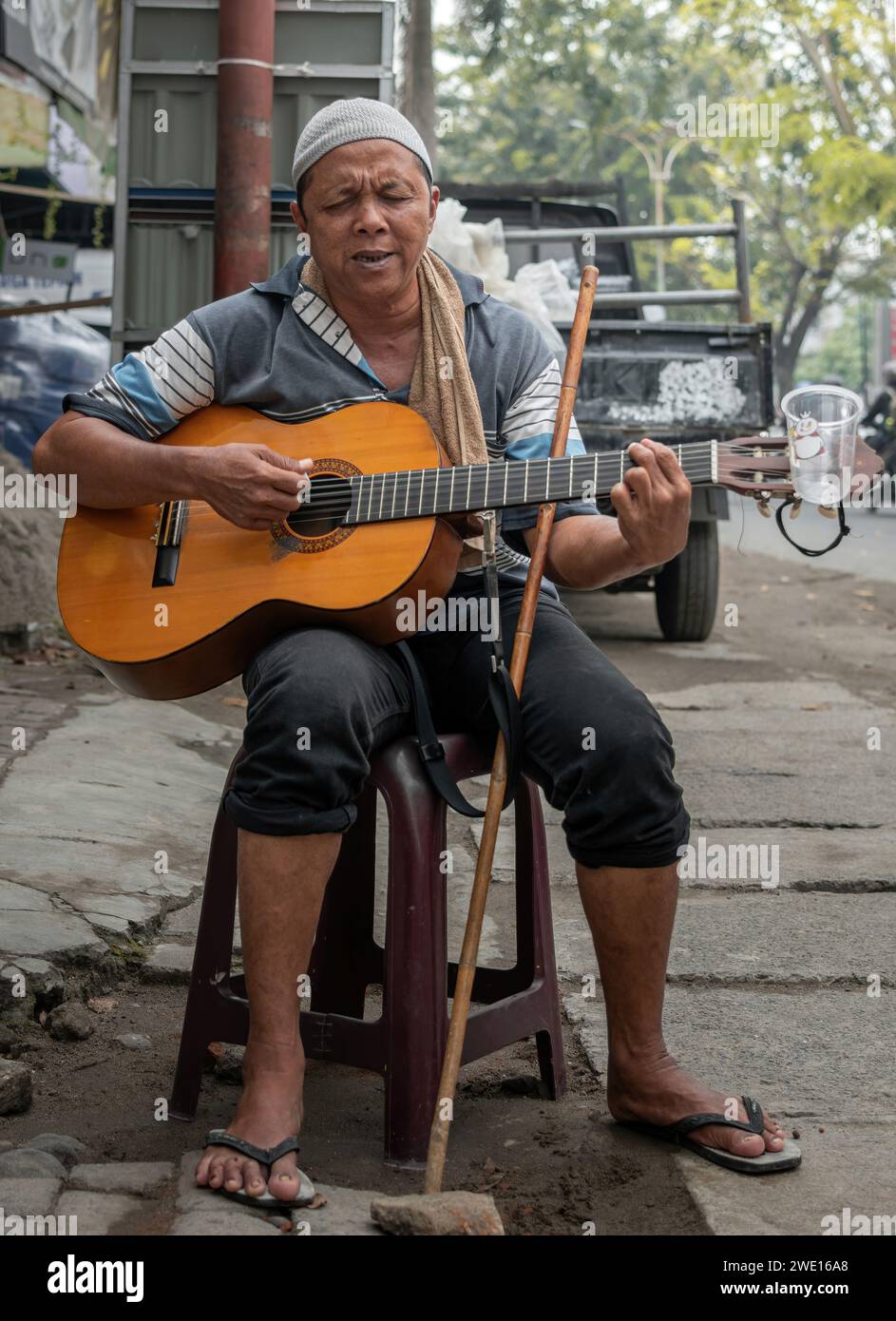 Un anziano musicista di strada cieco sta cantando e suonando la sua chitarra. Foto Stock