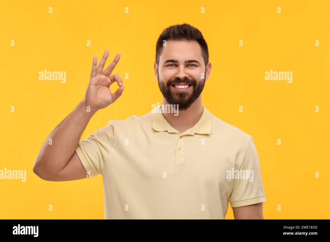 Uomo con denti puliti che mostra un gesto OK su sfondo giallo Foto Stock