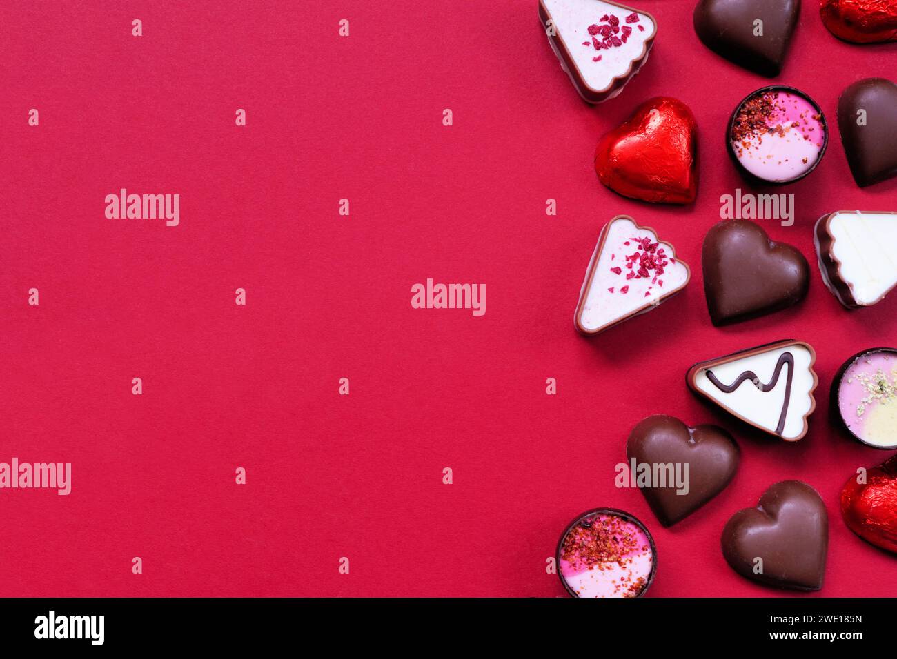 San Valentino, confine con cioccolato. Tema rosso e rosa. Vista superiore su uno sfondo di carta rosso con spazio per la copia. Foto Stock