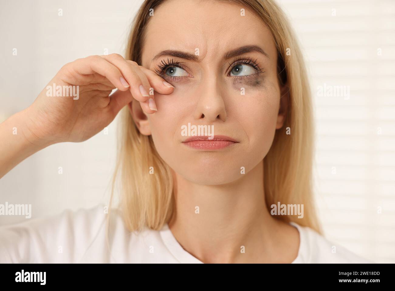 Donna triste con mascara strisciata che piange in casa, primo piano Foto Stock