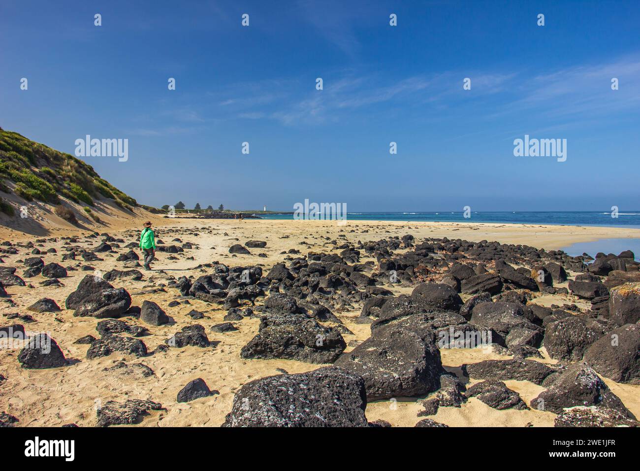 Rocce nere sparse sulla spiaggia sabbiosa di Griffiths Island di Port Fairy a Victoria, Australia. Foto Stock