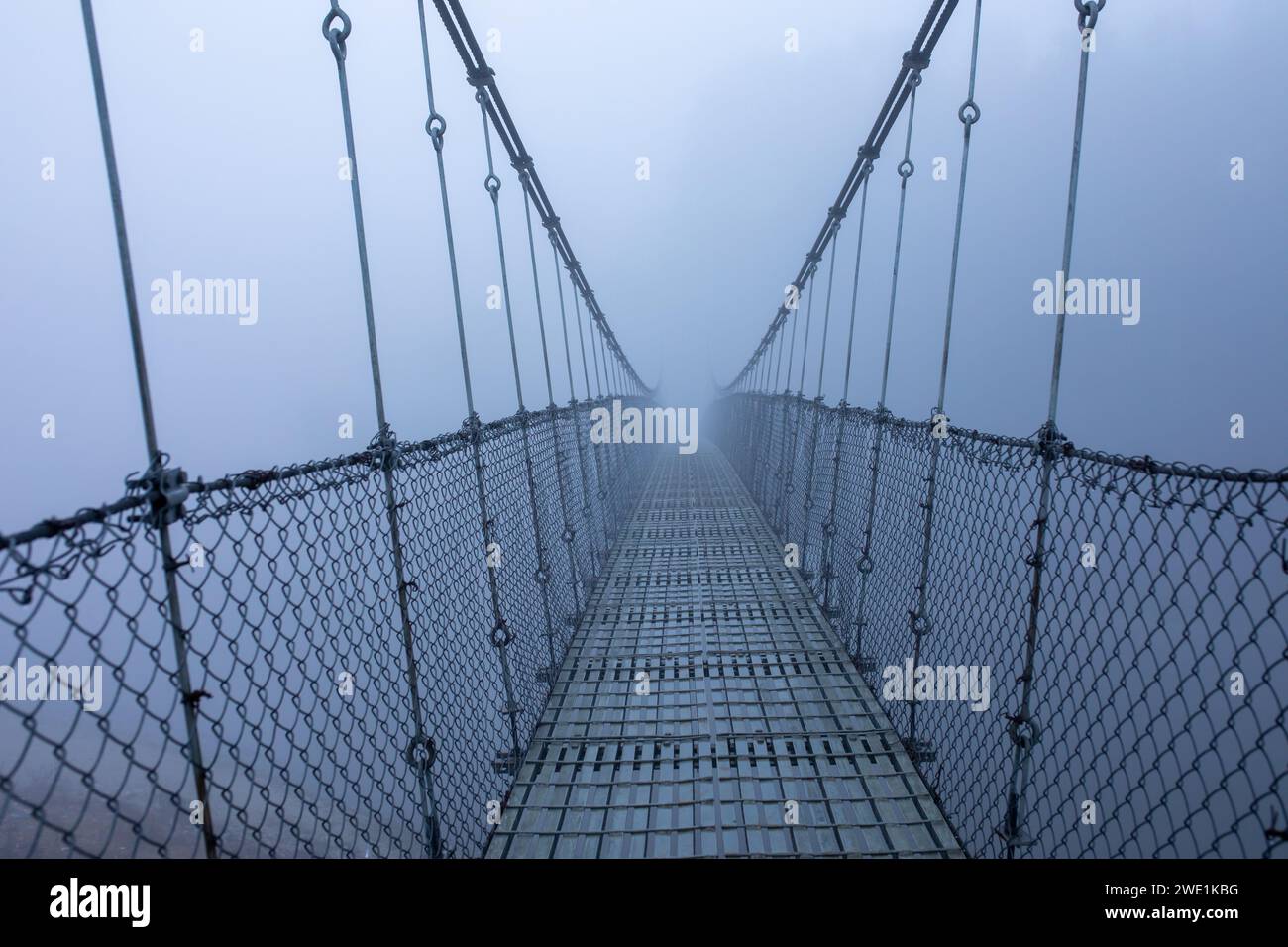 Foggy gelida mattina d'inverno, ponte sospeso. Foto Stock