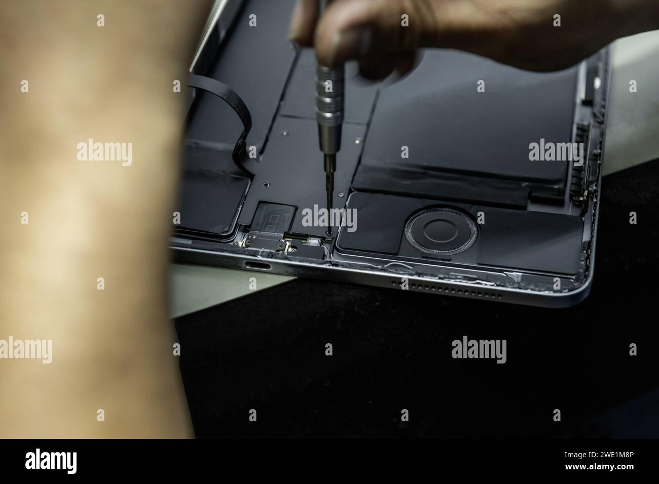 Un tecnico di un'officina di riparazione elettronica che avvita i componenti nella riparazione di un tablet Foto Stock