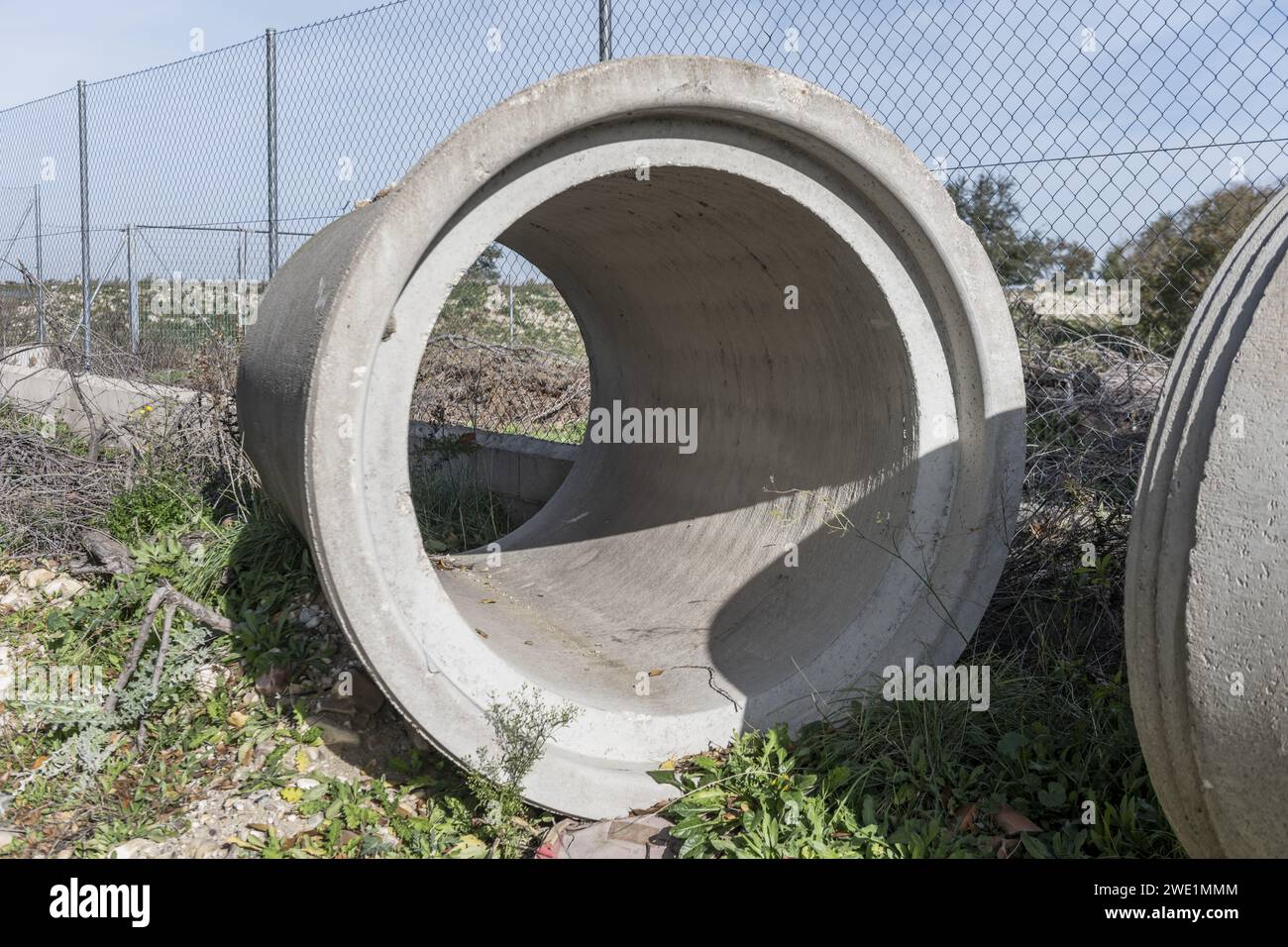 Alcuni grandi tubi di drenaggio in cemento abbandonati sul lato di una vecchia strada Foto Stock