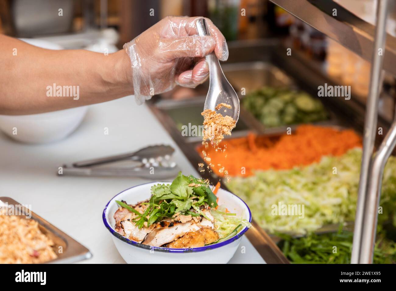 Lo chef prepara un piatto di spaghetti di pollo fresco alla griglia nella cucina del ristorante. Foto Stock