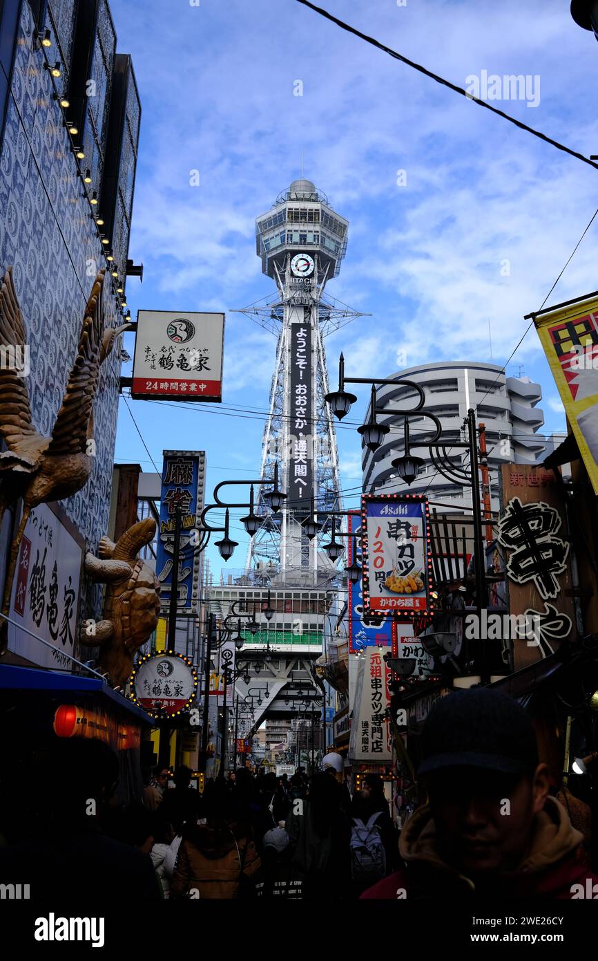 Tsutenkaku Tower nel quartiere di Shinsekai, Osaka, con una vivace scena stradale e cartellonistica tradizionale. Foto Stock