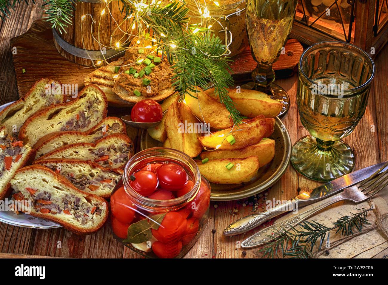 Tavolo festivo con torta di carne, patatine, patate e vino Foto Stock
