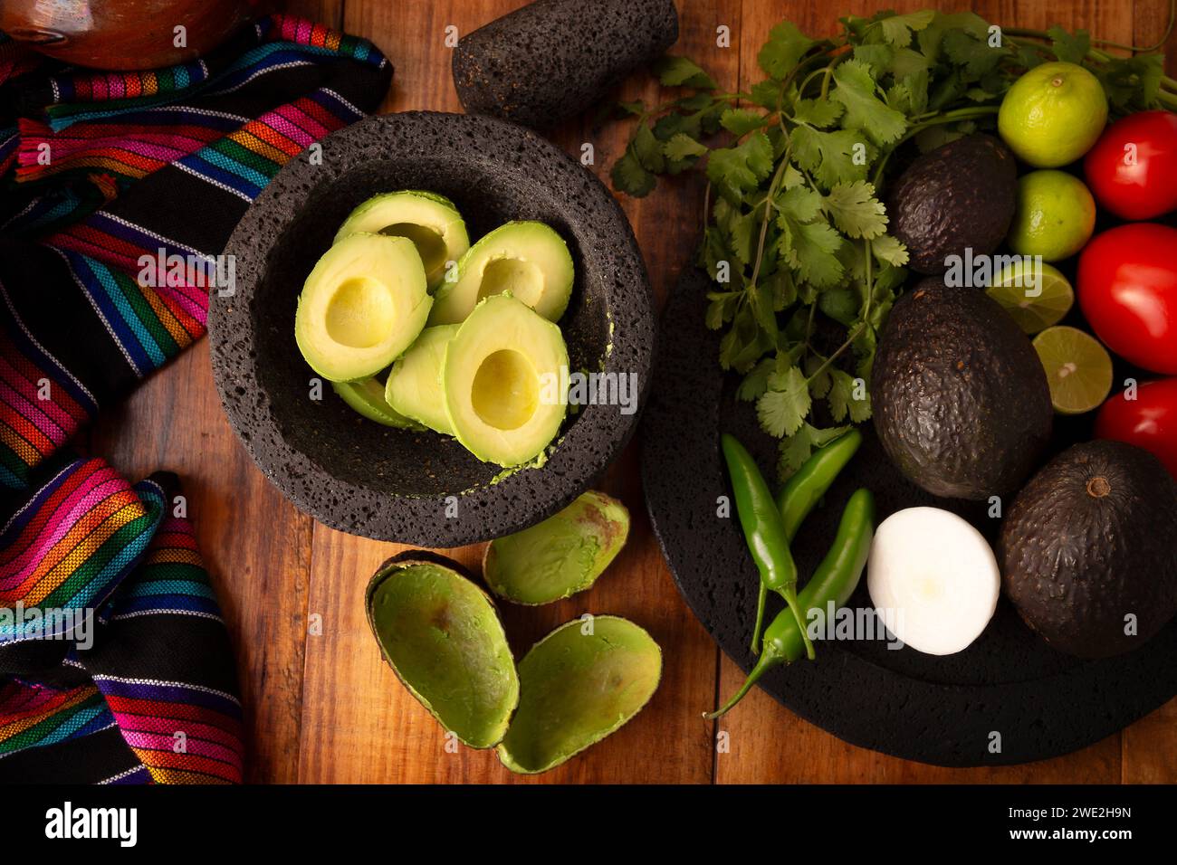 Ingredienti di base per preparare la salsa di avocado conosciuta come guacamole, realizzata in una molcajete di pietra vulcanica, una salsa molto popolare a base di avocado. Ricetta tradizionale Foto Stock