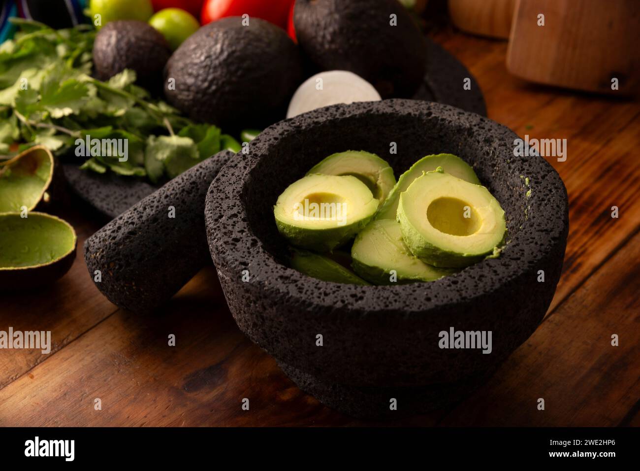 Ingredienti di base per preparare la salsa di avocado conosciuta come guacamole, realizzata in una molcajete di pietra vulcanica, una salsa molto popolare a base di avocado. Ricetta tradizionale Foto Stock