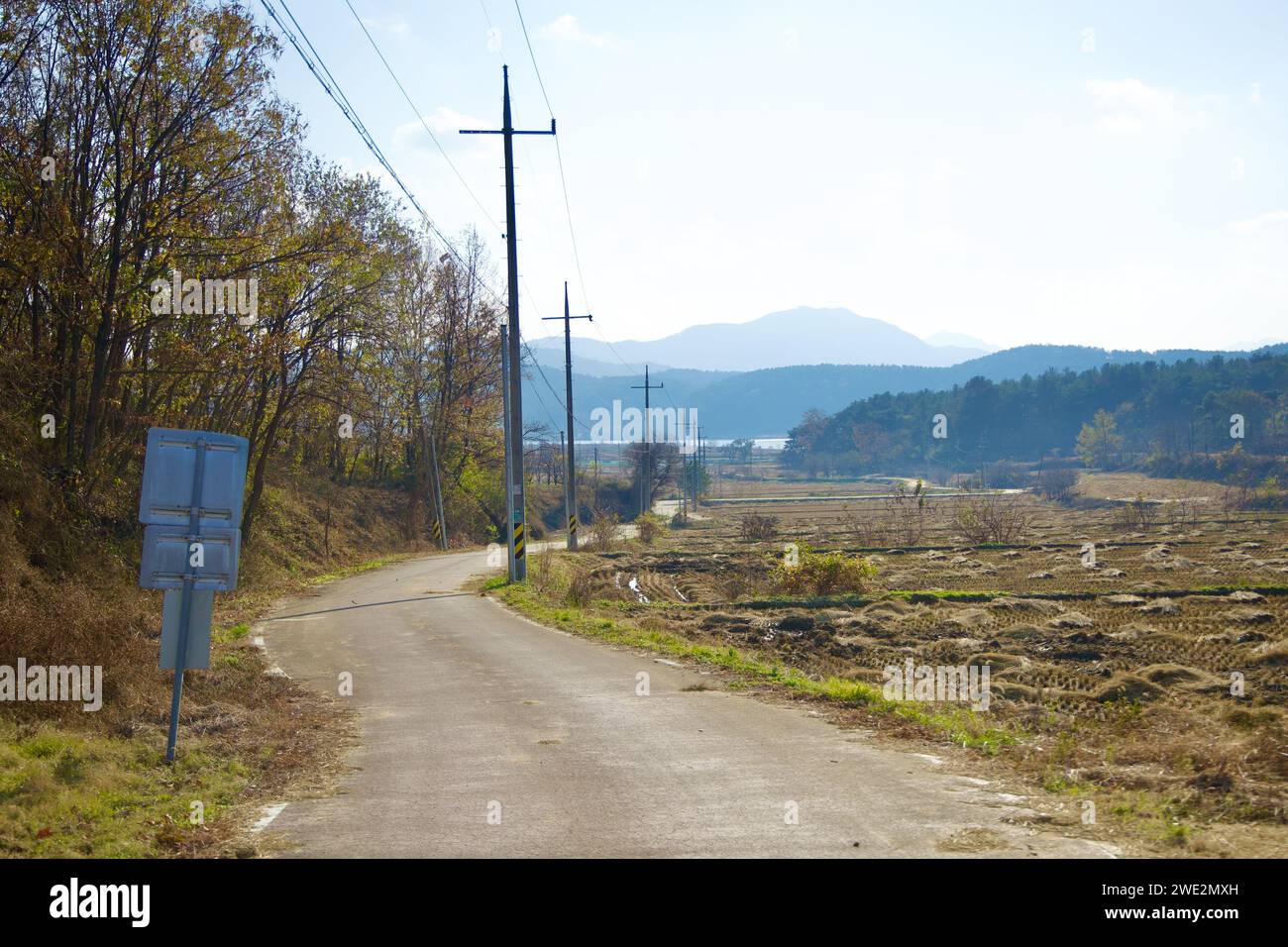 Città di Sangju, Corea del Sud - 18 novembre 2023: La pista ciclabile del fiume Nakdong si snoda attraverso campi agricoli post-raccolta, con linee elettriche sopraelevate e d Foto Stock