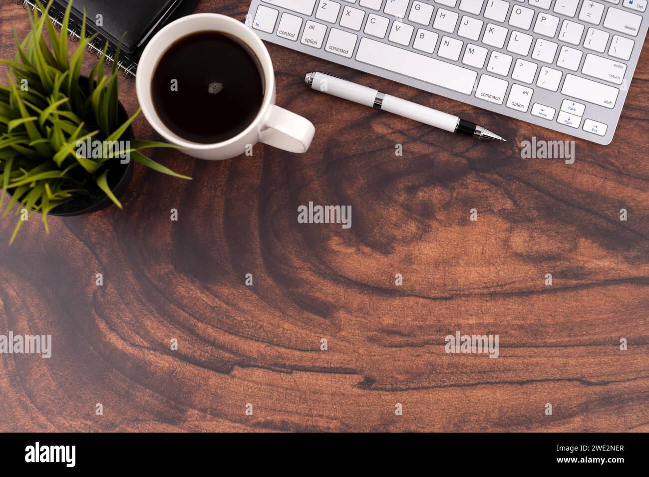 Scrivania in legno con caffè, penna e tastiera per computer Foto Stock