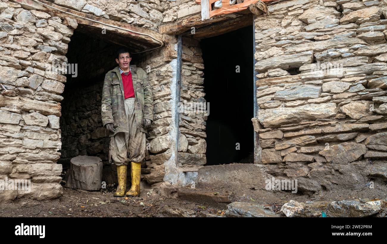 Hizan, Bitlis, Turchia - 3 gennaio 2020: Giovane in piedi presso una casa in pietra, a Hizan, un remoto villaggio nella Turchia orientale Foto Stock