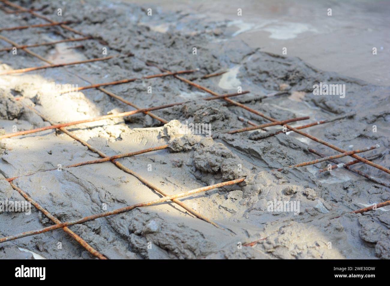Primo piano di una rete metallica saldata in una lastra di pavimento in calcestruzzo. Rete della barra di rinforzo installata orizzontalmente nel pavimento di cemento. Foto Stock