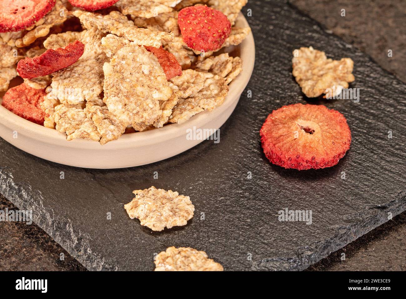 Iniziate la giornata con una sana colazione a base di fiocchi di grano con fragole dolci e secche e un pizzico di latte fresco, una deliziosa e nutriente bevanda Foto Stock